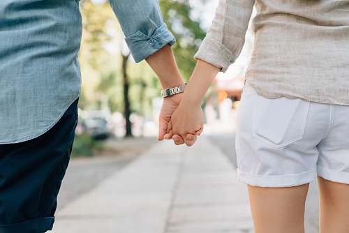 holding hands man and woman holding hands together in walkway during daytime people